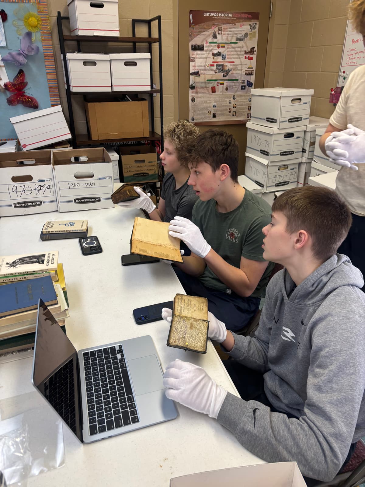 Žiburio student archivists examining books from the collection